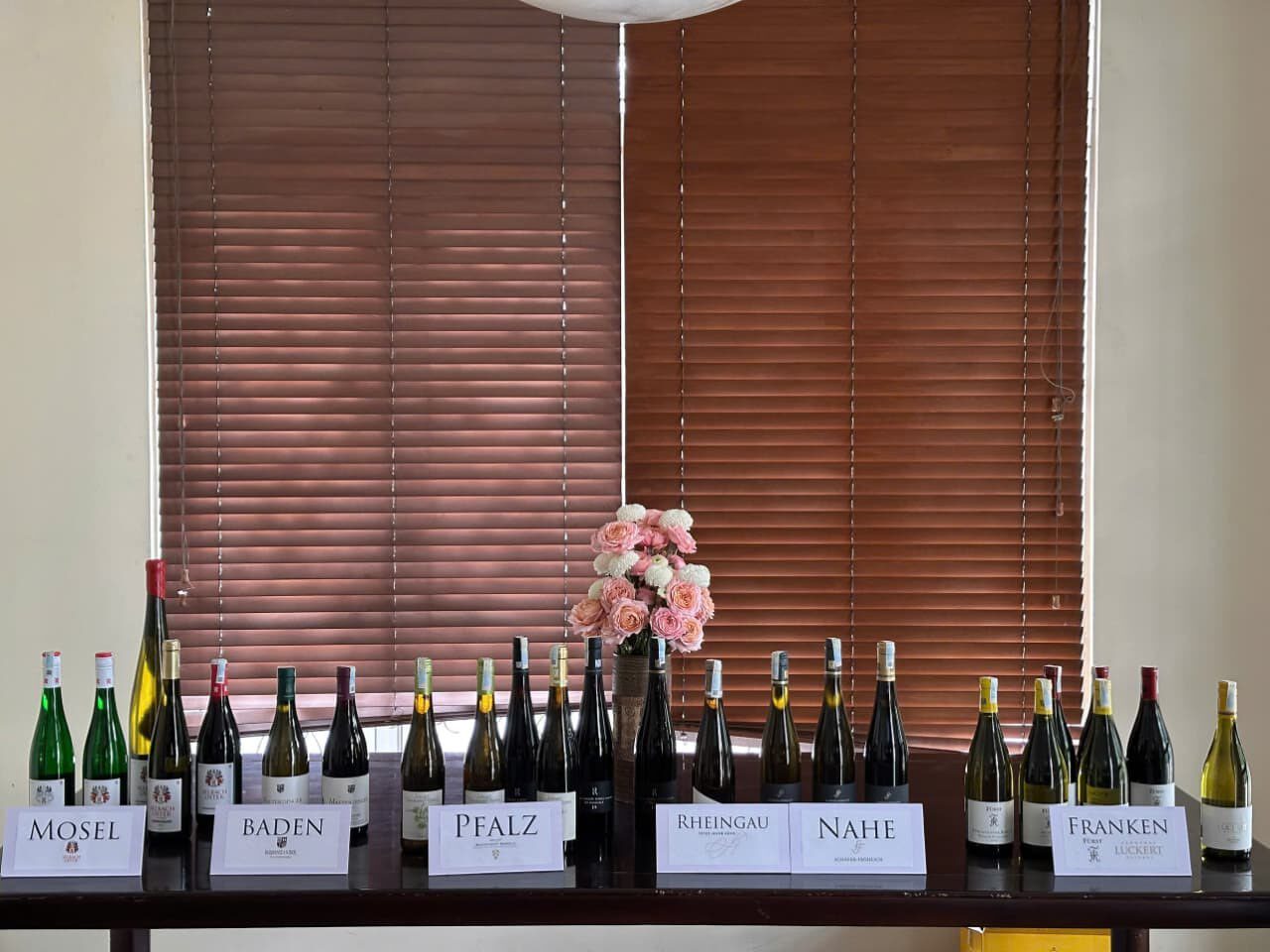 German wine bottles lined up on a long table with region cards for Mosel, Baden, Pfalz, Rheingau, Nahe and Franken