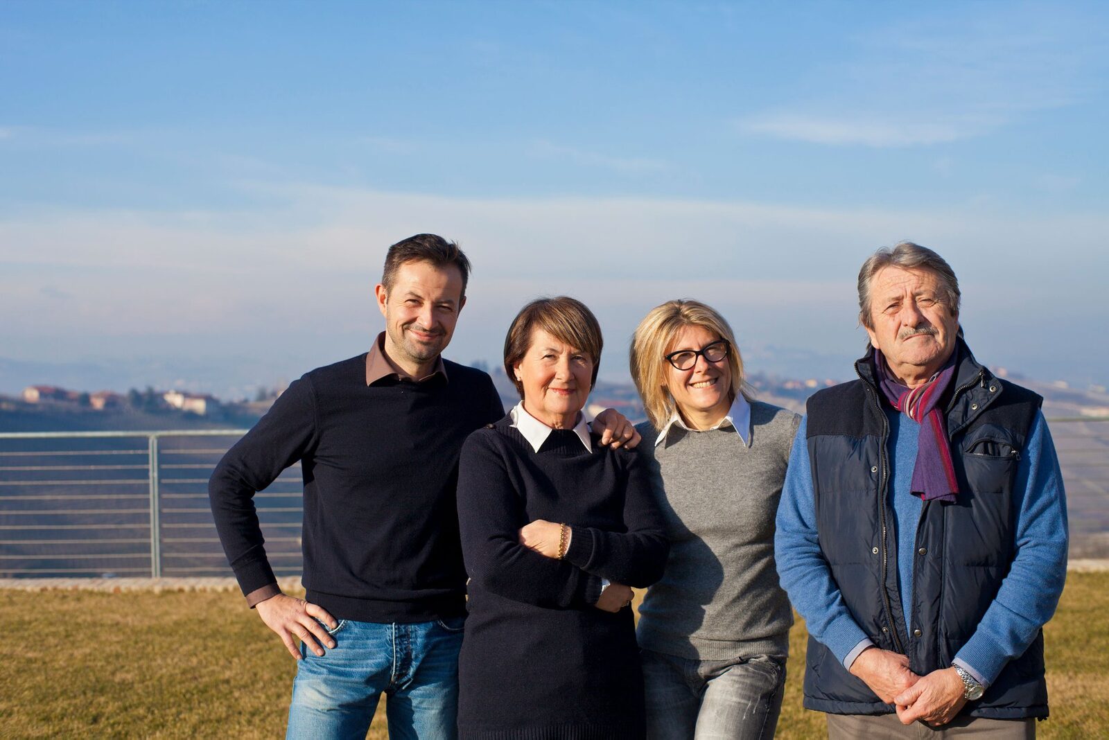 Four members of the Sottimano family standing outdoors with Piedmont hills behind them